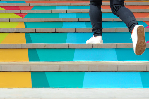 Lower part of teenage girl in casual shoe walking up outdoor colorful stair,teenage lifestyle successful concept