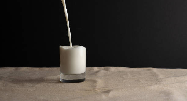 istock Pouring milk into invisible glass, abstract creative idea. Copy space, black background. 1145035755