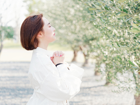 Portrait of a beautiful Chinese woman in white shirt stand in orchard in sunny day, cute girl praying for her lover, perfect side face.