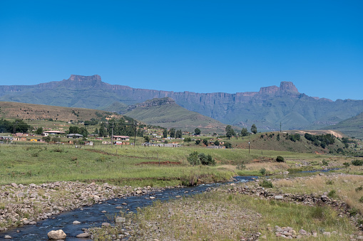 A few structures stand in a village in the valleys of the Drakensberg mountains in South Africa, the Tugela river flows through the valley
