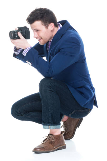 istock Side view of handsome man crouching while holding DSLR camera 1145045318