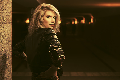 Young fashion blond woman with bob hair in a subway Stylish female model wearing black leather jacket