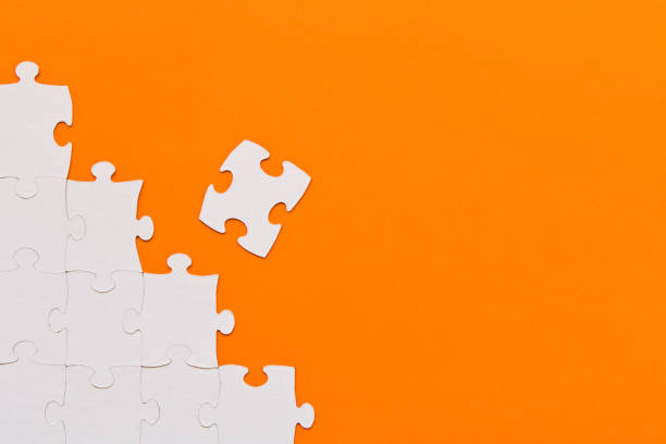 istock White jigsaw puzzles on orange background. The concept of development of thinking. 1145048433