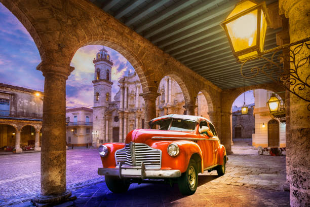 Vintage red oldtimer car driving through Old Havana Cuba at dawn
