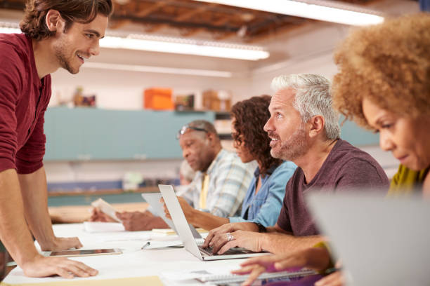 istock Teacher Helping Mature Man Attending IT Class In Community Centre 1145049522