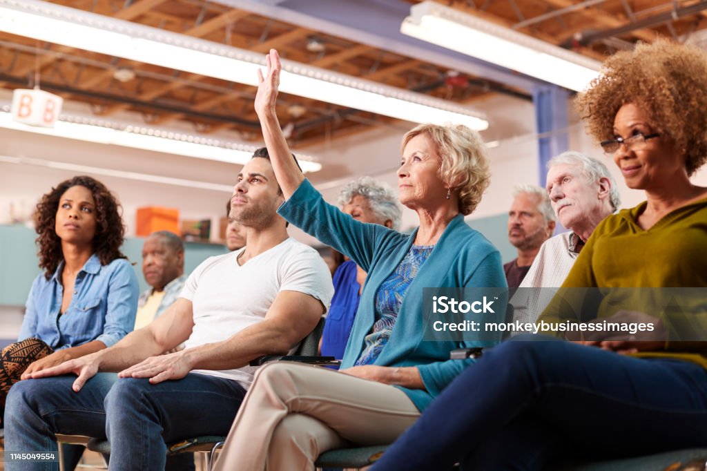 Woman Asking Question At Neighborhood Meeting In Community Center Meeting Stock Photo