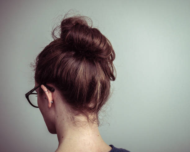 Caucasian woman from behind with brown hair in a ponytail Caucasian woman with glasses, from behind showing brown hair in a ponytail back of head photos stock pictures, royalty-free photos & images
