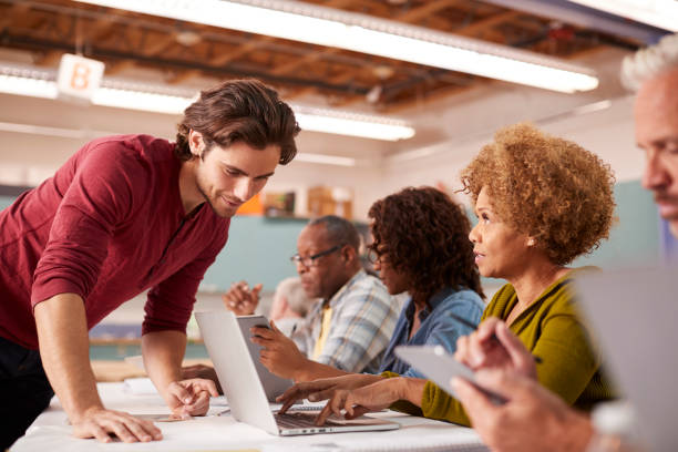 istock Teacher Helping Mature Woman Attending IT Class In Community Centre 1145050972