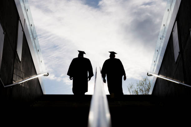 istock Silhouette of Two College Graduates Climbing Steps 1145052911