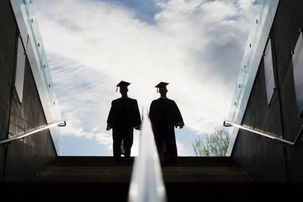 Photo of Silhouette of Two College Graduates Climbing Steps