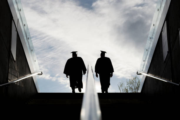 istock Silhouette of Two College Graduates Climbing Steps 1145052913