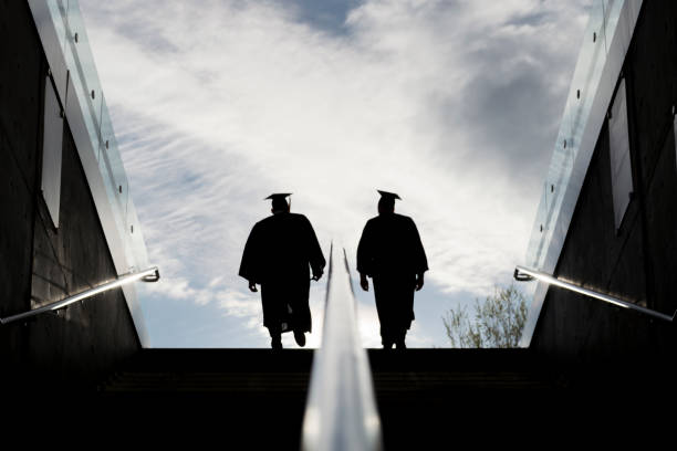Silhouette of Two College Graduates Climbing Steps stock photo