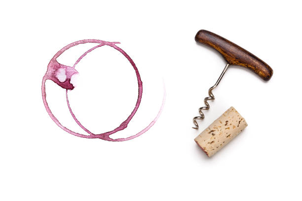 Red wine glass stains, corckscrew and wine cork Top view of red wine glass stains with a vintage corkscrew and wine cork beside it shot on white background. cork material stock pictures, royalty-free photos & images