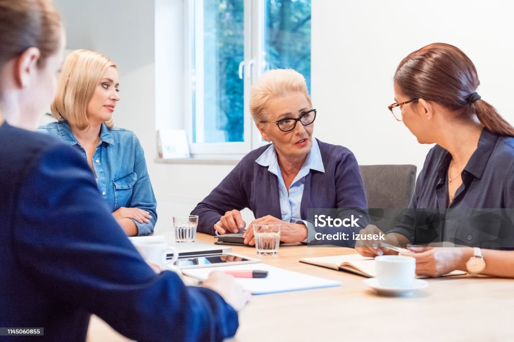 Colleagues having business discussion in meeting Female colleagues having business discussion at meeting. Confident entrepreneurs are planning strategy in office. They are sitting in board room. 35-39 Years Stock Photo