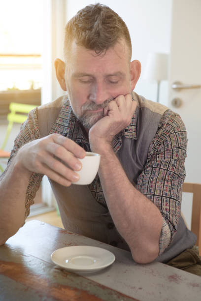 istock handsome man in his 50s sitting at table and drinking coffee 1145060880