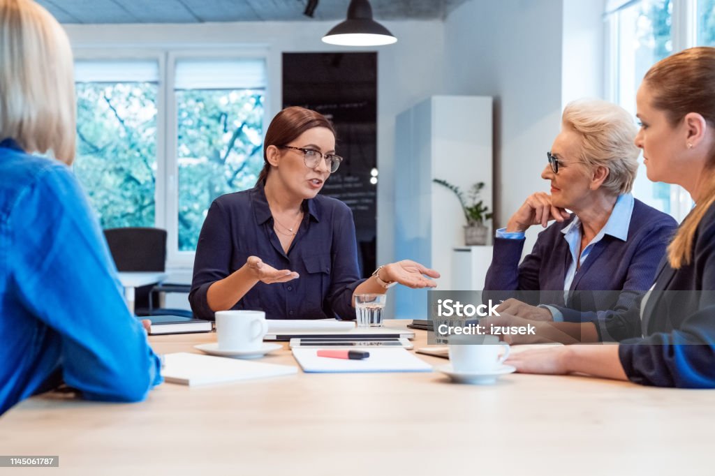 Executive discussing with colleagues in meeting Mature businesswoman discussing with colleagues. Female professionals are planning in meeting. They are sitting at board room in office. 35-39 Years Stock Photo