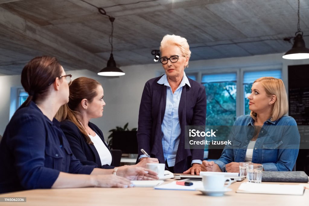Smiling female entrepreneurs in meeting at office Confident elderly expertise discussing plans with businesswomen. Female professionals are building new strategy together. They are working in start-up office. 35-39 Years Stock Photo