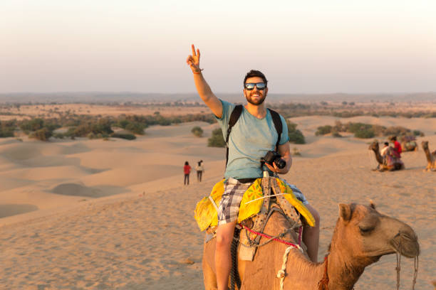 turista montando en camello en desert - viaje fotos fotografías e imágenes de stock