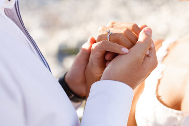Close up of a hands of woman and man just married, with natural sunset light, holding tender in hands. stock photo