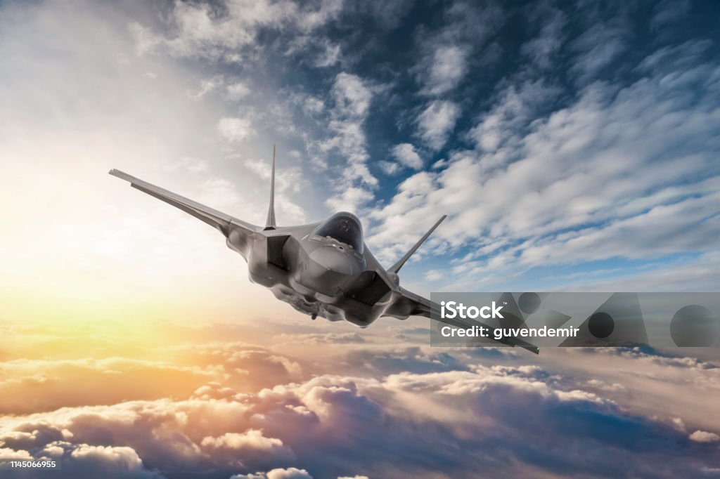Fighter Jet flying over the clouds at sunset Fighter Plane Stock Photo
