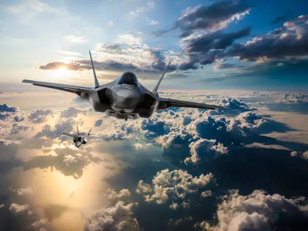 Photo of F-35 Fighter Jets flying over the clouds at sunset