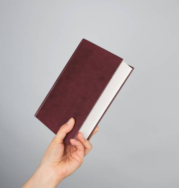 istock hand holds a closed book in hardcover 1145072731