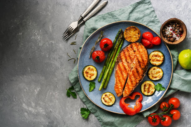 野菜のグリルサーモンズッキーニ、アスパラガス、トマト、ピーマン、皿、灰色の背景。トップビュー、フラットレイ、コピースペース - cooked pepper salmon food ストックフォトと画像