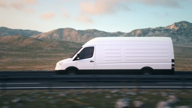 white delivery van driving along a desert road into the sunset