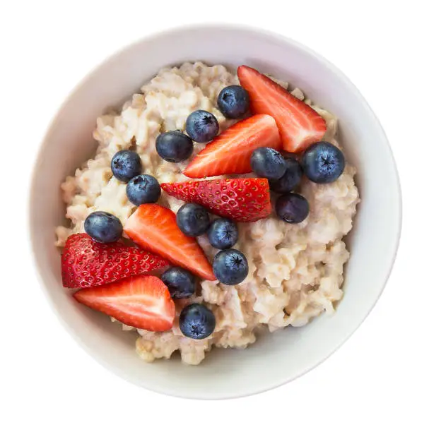 Photo of Homemade oatmeal with blueberries and strawberries in bowl isolated on white background