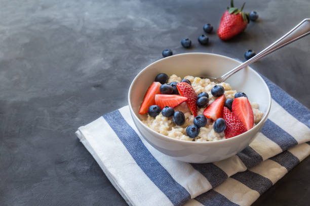 istock Homemade oatmeal with blueberries and strawberries in bowl on gray concrete background 1145080098