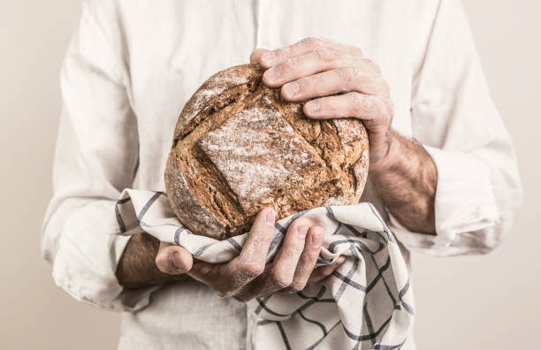 istock Rustic crusty loaf of bread in baker man's hands 1145081797