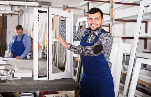 Workman is demonstrating the window frame in workshop.