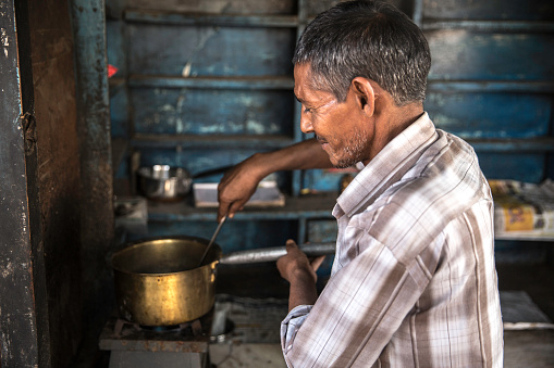 Bhopal, Madhya Pradesh, India - March 2019: An Indian man making tea at his rustic roadside chai stall in the city.