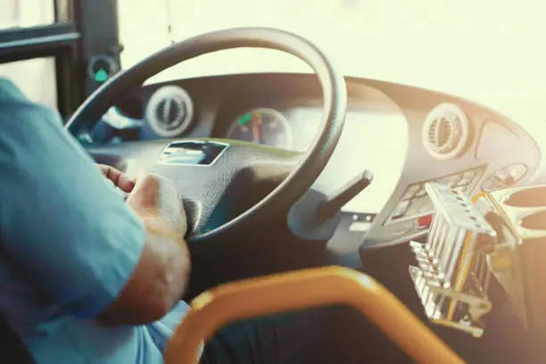 Hands of driver in a modern bus by driving. Concept of bus driver steering wheel and driving passenger bus. Toning.
