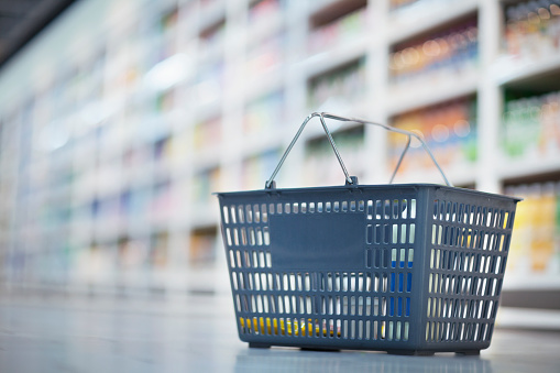 Shopping basket on floor in supermarket aisle