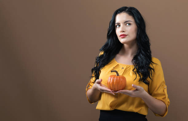 istock Young woman holding a pumpkin 1145097724