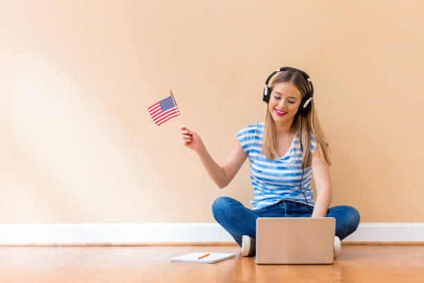 Young woman with USA flag using a laptop computer Young woman with USA flag using a laptop computer against a big interior wall usa england stock pictures, royalty-free photos & images