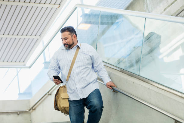 istock Hispanic man walking, looking at mobile phone 1145099057