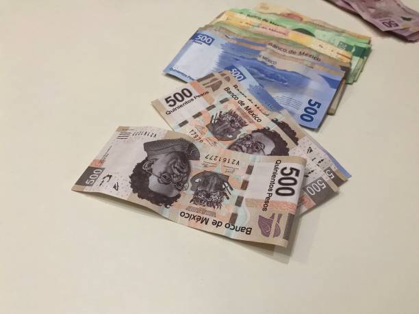 istock Many mexican pesos bills spread over a beige colored desk inside a small business office 1145102813