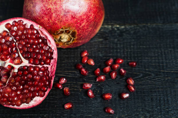 istock Ripe pomegranate, pomegranate kernels on black wooden background. 1145105372