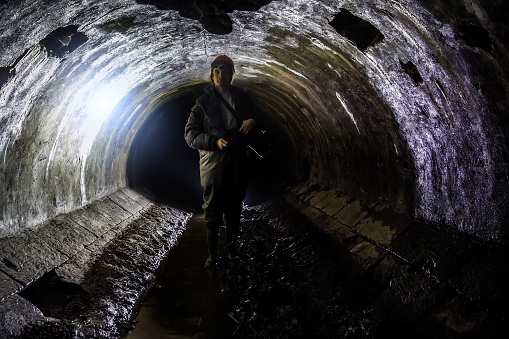 Sewer worker in underground sewer tunnel.