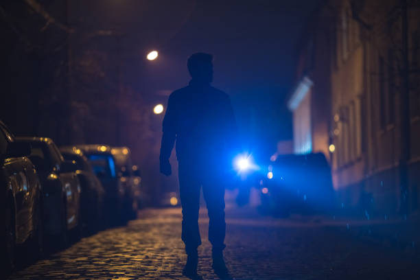 istock The man with a flashlight stand on wet road. Evening night time 1145106760