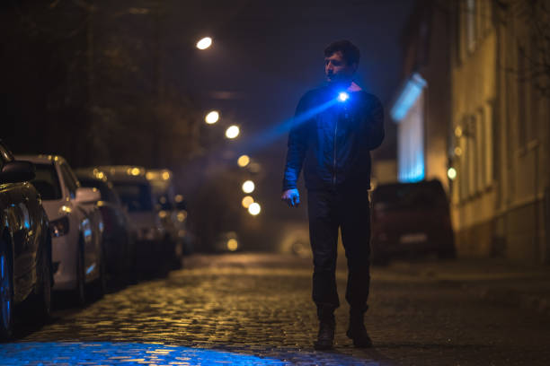 istock The man with a flashlight stand on wet road. Evening night time 1145106769