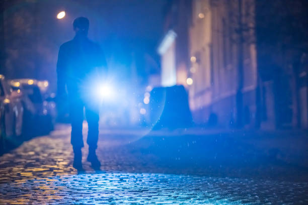 The man with a flashlight stand on the road. Evening night time