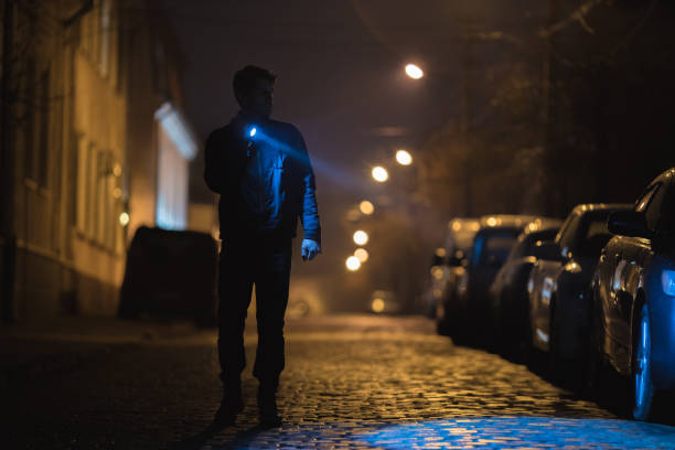 懐中電灯を持った男は濡れた道路に立っている。夜の夜の時間 - handsome man flash ストックフォトと画像