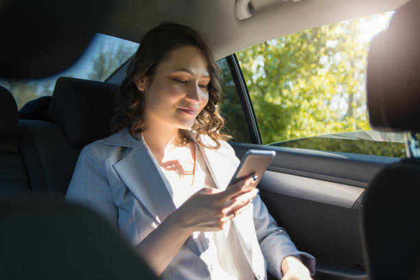 istock Successful businesswoman sending text message on smart phone while sitting on back seat in the car 1145111895