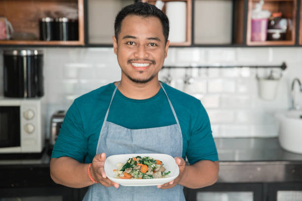 istock man with apron carrying food 1145115588