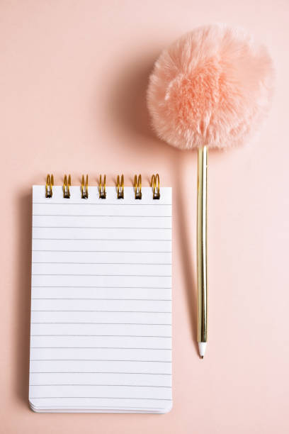 vista dall'alto del notebook vuoto con divertente penna soffice su sfondo pastello rosa con spazio di copia, composizione verticale - lanuginoso foto e immagini stock