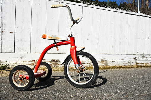 An image of an old red tricycle in an empty school playground