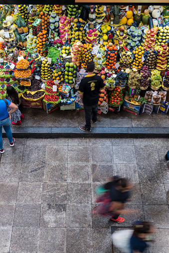 São Paulo, São Paulo, Brazil. 23rd April 2019. Man looking at fruits on market stall in Municipal Market downtown, São Paulo. People passing.